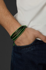 Cropped close-up shot of a male wrist with a multilayer bracelet with strings. The double-colored...