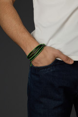 Cropped shot of a male wrist with a multilayer bracelet with strings. The double-colored bracelet...