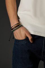 Cropped shot of a male wrist with a multilayer leather bracelet made of wax ropes and leather...