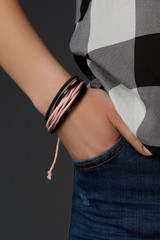 Cropped close-up shot of a female wrist with a multilayer bracelet with strings. The double-colored...