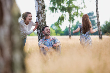 Fototapeta premium Loving mother plays with her daughter in the woods whilst her husband watches on