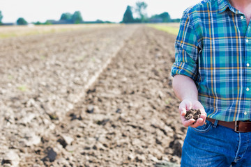 Crop photo of mature man showing soil in field