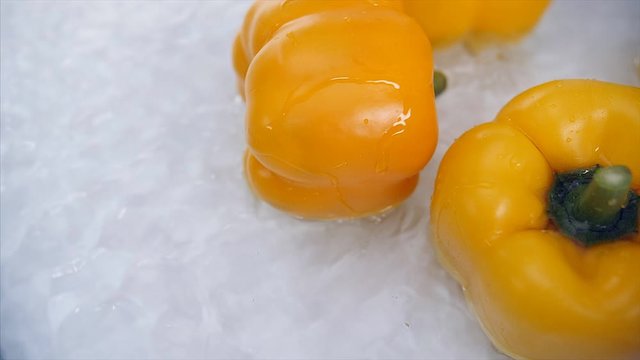 Slow motion close top shot of multiple yellow capsicum falling in water  . 