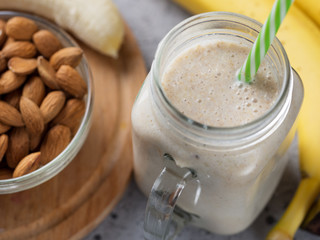 Fresh banana smoothie on a wooden table in a jar . With oatmeal and almonds