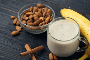 Fresh banana smoothie with almonds, oatmeal and cinnamon in a Cup on a wooden background