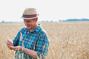 Happy farmer holding wheat grain in field