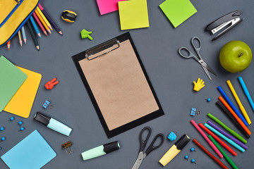 Flat lay photo of workspace desk with school accessories or office supplies on gray background.