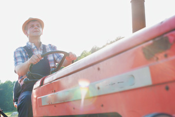 Mature farmer driving tractor in field