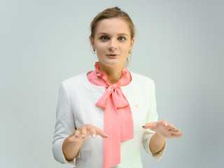 Photo studio portrait of a cute young woman girl in a beautiful suit of white-pink tender color on a white background. He stands right in front of the camera, explains with emotion.