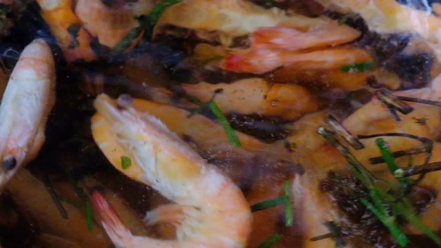 Medium-sized sea prawns are boiled in a pot of water with aromatic herbs, close up
