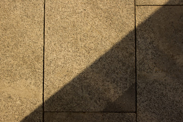 Fototapeta premium Paving slabs in shade from sun. Cityscape close-up view
