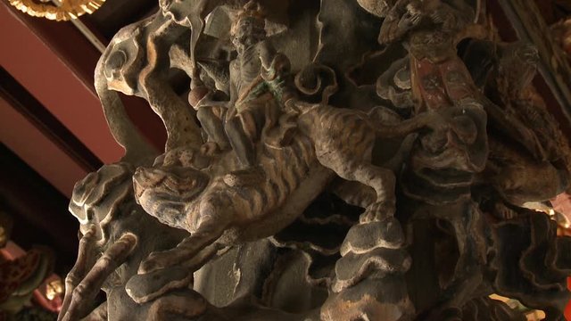 Extreme close-up low-angle still shot of an intricate stone carving of immortals and a tiger on a column, Georgetown, Penang, Malaysia