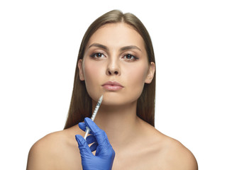 Close-up portrait of young woman on white studio background. Filling surgery procedure. Lip augmentation. Concept of women's health and beauty, cosmetology, self-care, body and skin care. Anti-aging.