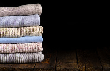 stack of clothes from knitted knitwear on a wooden background, toned image