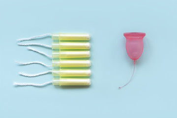 The female menstrual cup is contrasted with six tampons in the applicators. Zero waste concept.