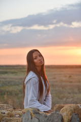 Naklejka premium girl in white clothes at sunset on the ruined wall