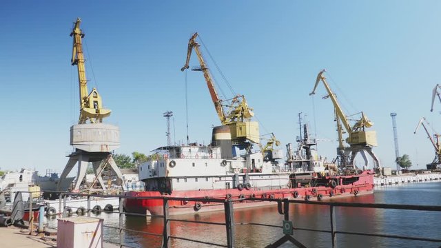 Sea port cranes. Commercial port steel in summer day. Urban landscape. Cargo ship at port. Construction of the ship in shipyard