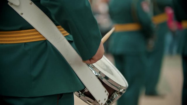 A wind instrument military parade - a man in costume hitting the snare with drum sticks