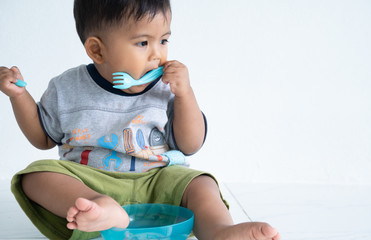Cute little asin baby boy with spoon