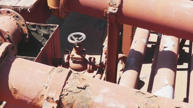 Black valve in thin red rusty pipes in sea ship. Machinery and equipment of a ship.