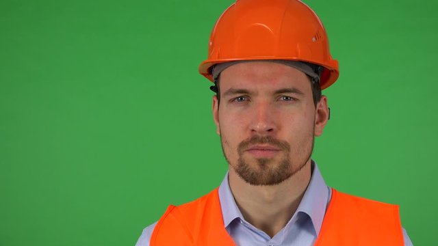 A young construction worker looks seriously at the camera - closeup - green screen studio