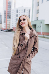 Fototapeta premium Close up street urban sexy portrait of young pretty sexual young caucasian blondie girl walking on city street in cloak and lingerie. Sexuality, beauty, fashion concept