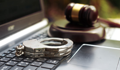 Wooden judge gavel and police handcuff on keyboard laptop.Concept of crime and punish cyber...
