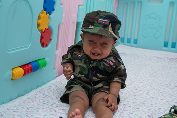 Naklejka premium Cute little asian baby in Military uniform play toy
