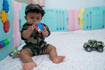 Fototapeta premium Cute little asian baby in Military uniform play toy