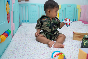 Cute little asian baby in Military uniform play toy