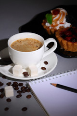 Cup of coffee, cakes and notebook on dark background
