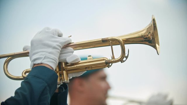A wind instrument military parade - a man playing trumpet outdoors