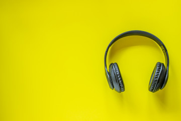 Black headphones on a yellow background. Minimal concept. Flat lay.