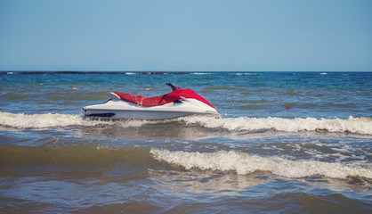 Red and white jet ski splashing on waves