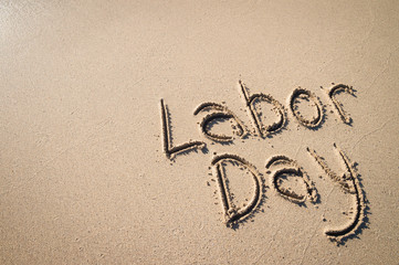 Simple Labor Day message handwritten on an empty beach with smooth sand copy space