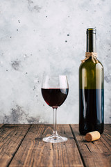 Red wine, glass and bottle on a stucco wall