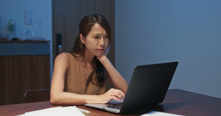 Woman feeling tired on look at the laptop computer at home in the evening