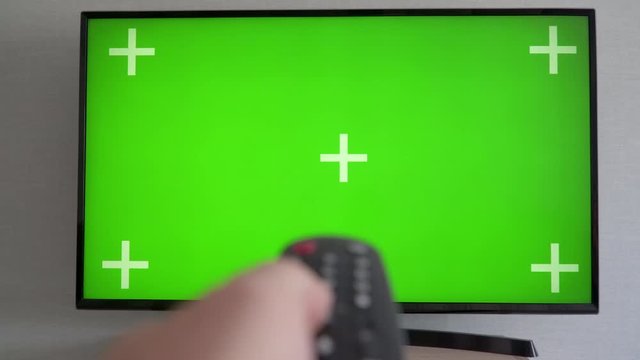 Flat screen TV with green screen composited Male hand holding the TV remote control Channel surfing Internet TV