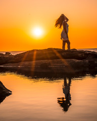 A young woman in white dress in a beautiful sunset. Lifestyle session, vertical photo