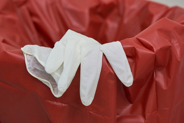 A used surgical glove on the red bin