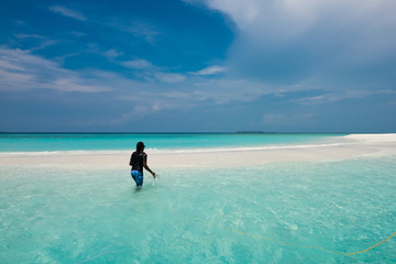 Man plants an anchor on a beach in the Maldives