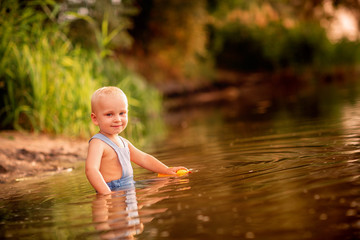 Cute baby boy playing on the river bank