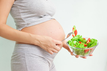 healthy nutrition and pregnancy. pregnant woman's belly and vegetable salad. Pregnancy Nutrition....