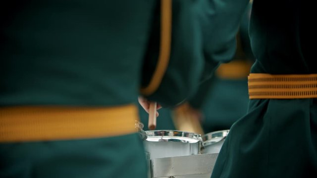 A wind instrument military parade - people in green costumes playing drums outdoors