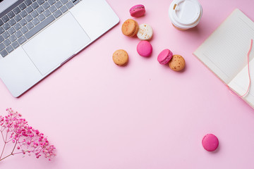 Flatlay with laptop, coffee and macarons on pink background. Top view, copy space. Workplace concept.
