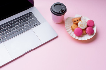 Obraz na płótnie Canvas Flatlay with laptop, coffee and macarons on pink background. Top view, copy space. Workplace concept.