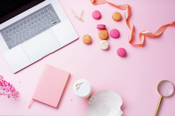 Flatlay with laptop, coffee and macarons on pink background. Top view, copy space. Workplace concept.