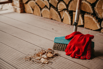 Brush for cleaning stands on veranda. Red gloves on top