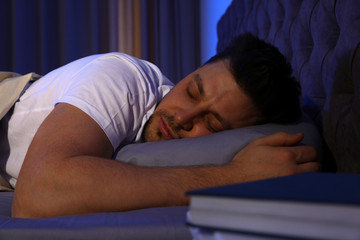 Handsome man sleeping on pillow in dark room at night. Bedtime