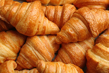 Fresh tasty croissants as background, closeup. French pastry